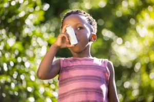 Boy using a asthma inhalator in a park. 