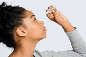 A woman putting eye drops in her eye 