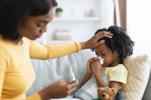 Young girl wiping her nose having her temperature taken 