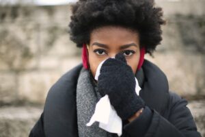 A young woman protecting her nose against the cold with a white handkerchief 