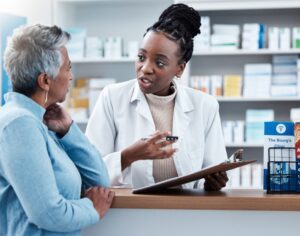 Pharmacy, medical or insurance with a customer and black woman pharmacist in adispensary. Healthcare, clipboard and trust with a female medicine professional helping a patient in adrugstore.