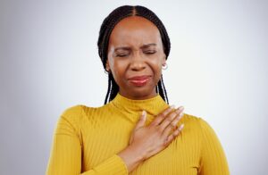 Heart pain, black woman and ache with stress, anxiety and problem from cardiology crisis in studio. White background, African female person and heartburn. 