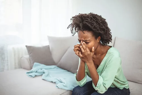 Photograph of a woman sitting on a bed feeling despondent