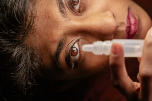 A close-up view of a woman using eye drops, using water-based eye drop, Pharmacy, medication, Medical, medicine, from the top angle view.