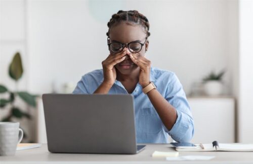 Eye Strain. Tired African American Female Office Worker Sitting At Workplace Massaging Nosebridge, Wearing Glasses, Exhausted After Working On Laptop Computer, Having Eyesight Problem, Copy Space.