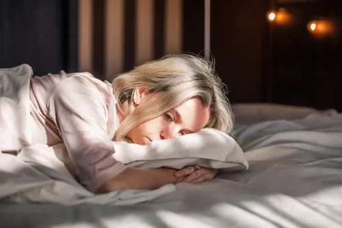 Tired middle-aged woman lying in bed can't sleep late at morning with insomnia. Adult lady sick or sad depressed sleeping at home.