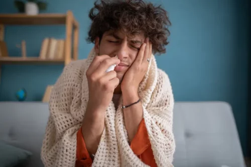 Young Arabic man using nasal spray to help with cold. Sick with a rhinitis man dripping nose. Applies nasal spray.