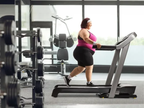 Overweight woman walking on a treadmill at the gym.