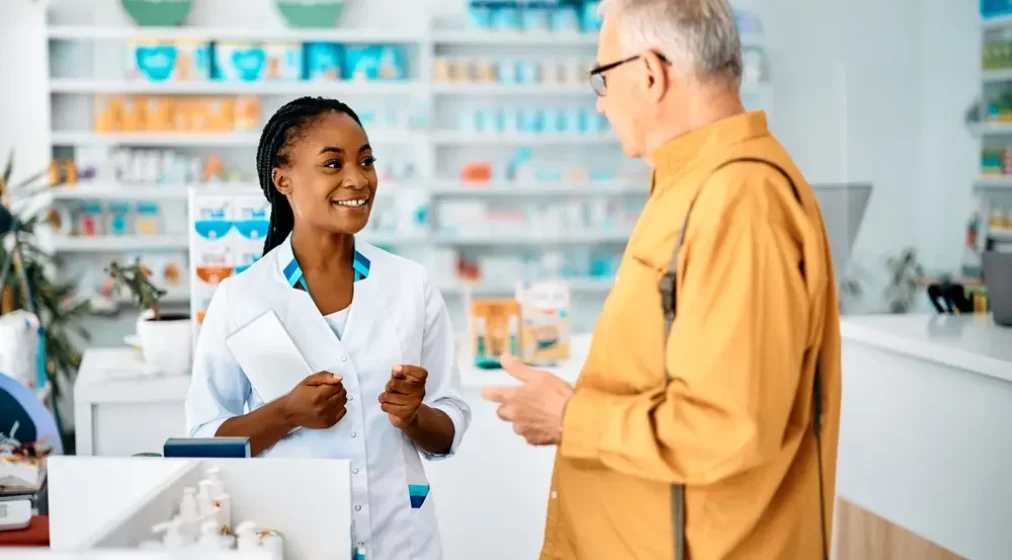 Young African American female pharmacist advising senior man in drugstore.