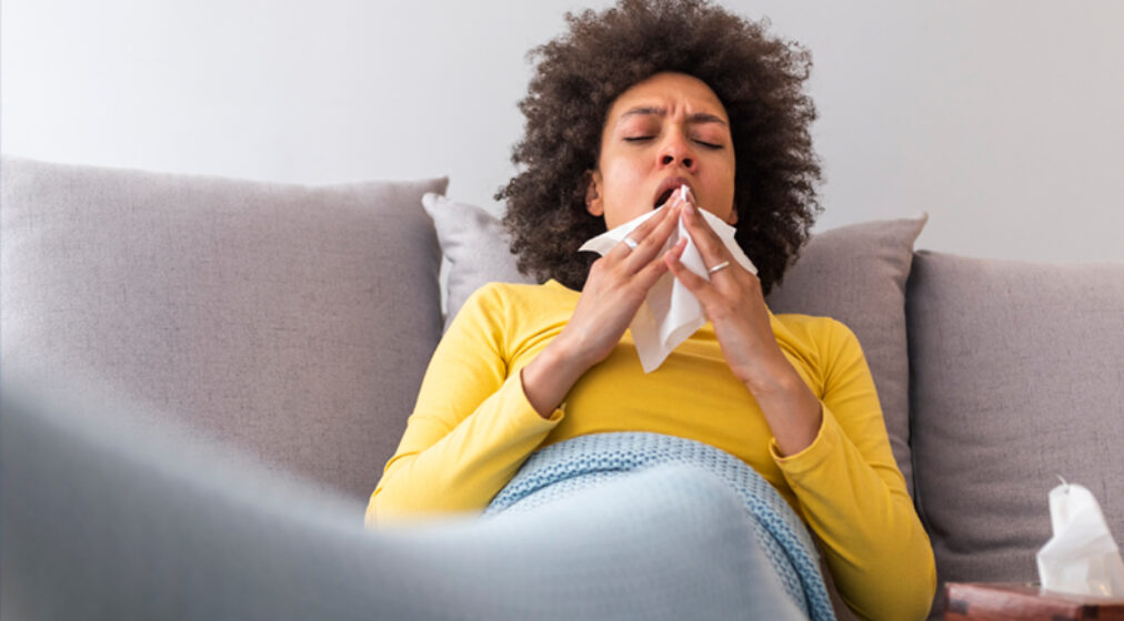 lady sneezing sitting on a couch